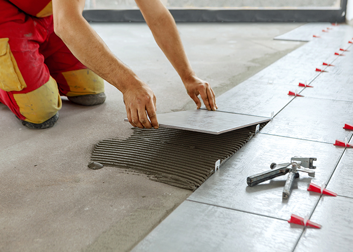 Pose de carrelage avec Ng Réno à Cuxac-Cabardès, carreleur installant des carreaux de sol sur chantier lumineux,